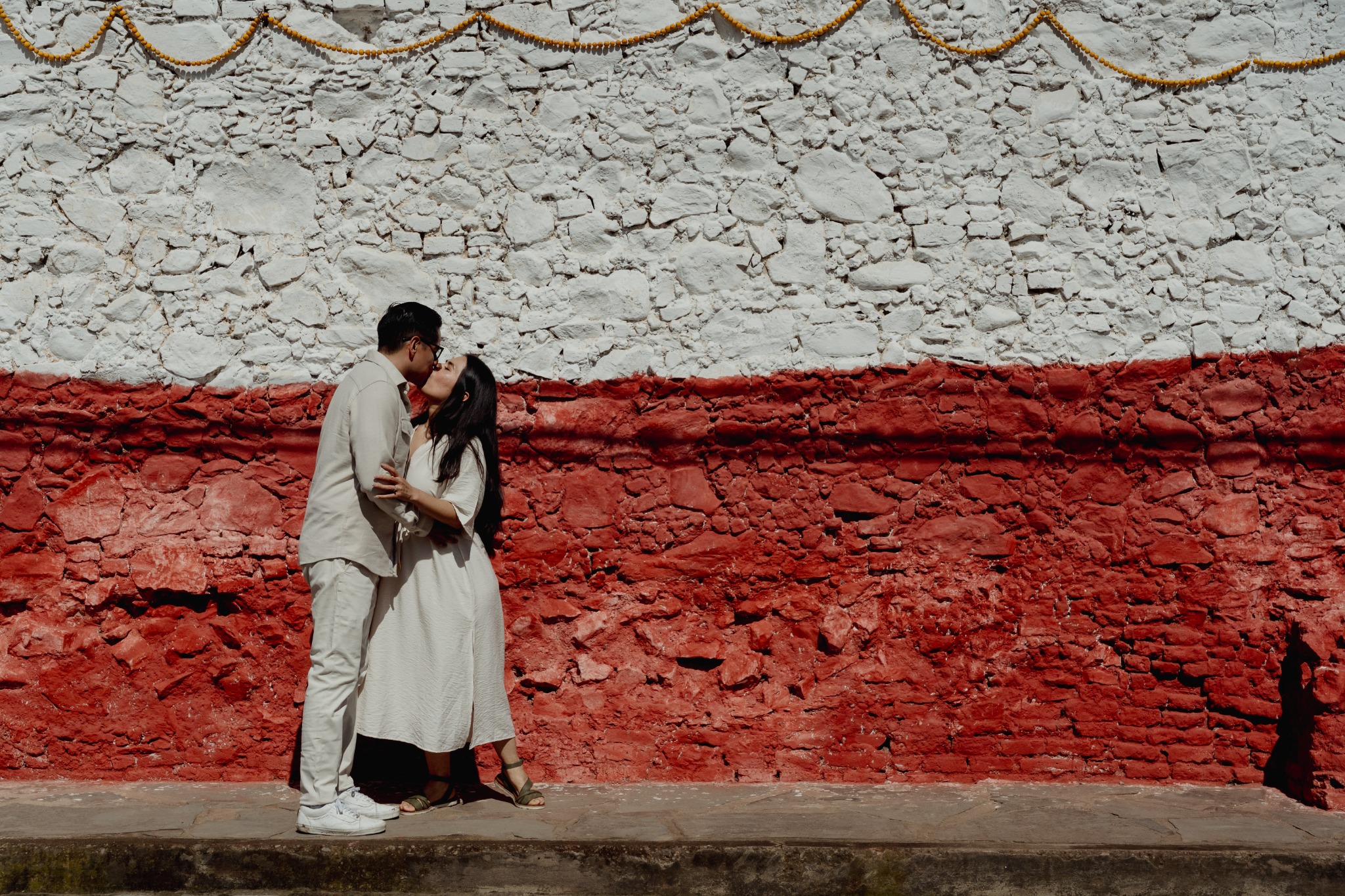 Rosa María y Joacim besándose frente al muro rojo